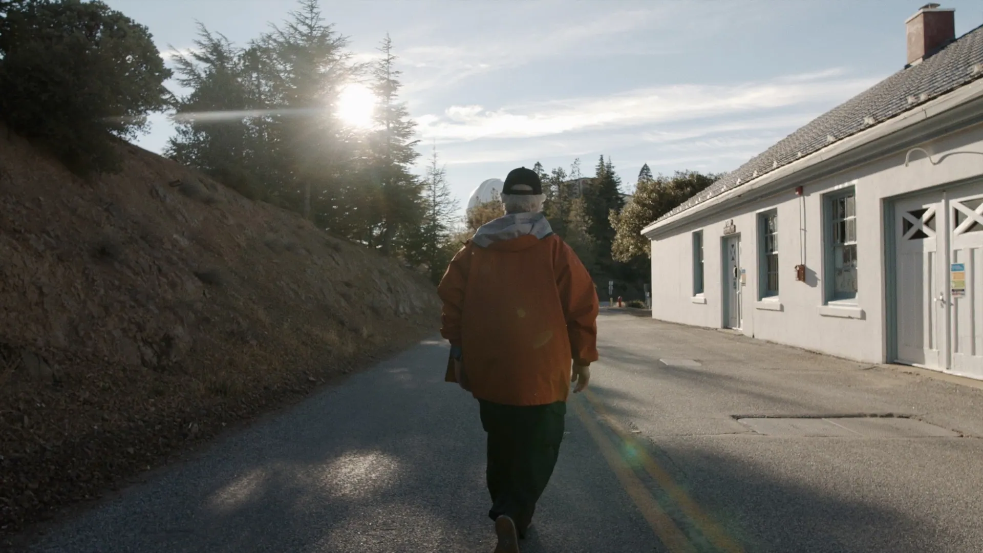 Astronomer walking toward an observatory dome at sunset